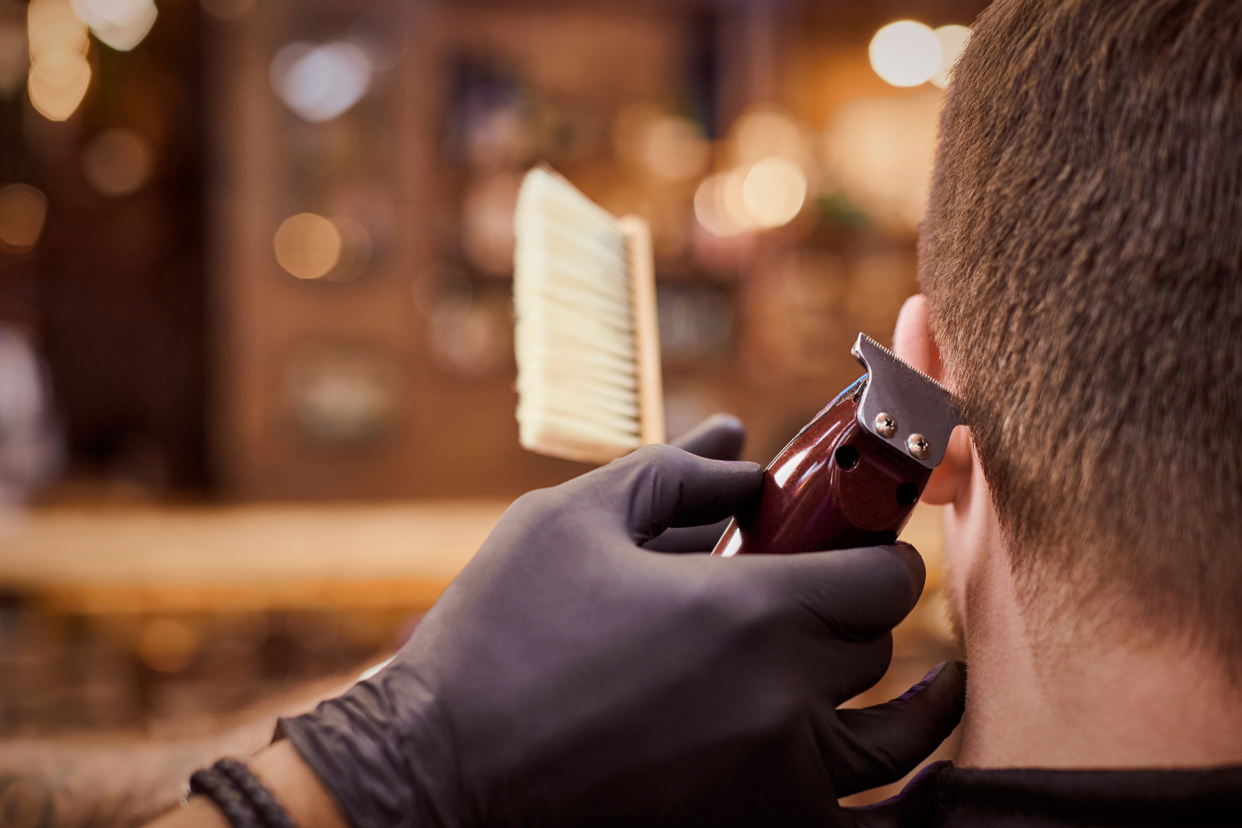 Male haircut trimming in barbershop, client getting haircut by hairdresser with clipper, hairbrush